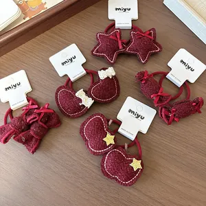 Detailopname van wijnrode haarelastiekjes met strik en witte stiksels op hout