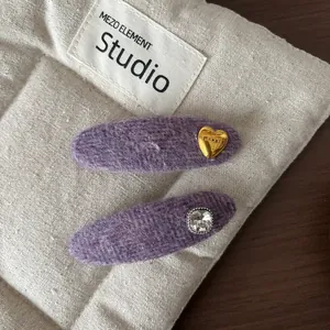 Detail of purple knitted hair clips with gold heart metal piece and square rhinestone