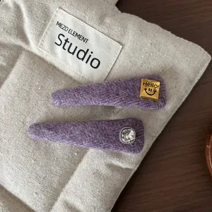 Detail of purple wool felt hair clips featuring a Hello gold plate and square rhinestone