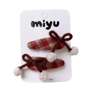 Set of two red plaid hair clips with brown knit bows and white pompoms for girls