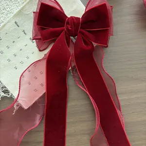 Dettaglio macro del fiocco in velluto bordeaux con bordi in organza e nastri lunghi