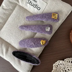 Detail of purple plush BB clips featuring gold smile heart and rhinestone decorations