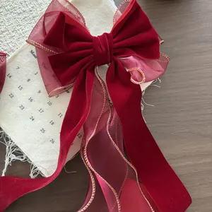 Dettaglio del fiocco per capelli in velluto bordeaux e organza con bordi dorati