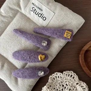 Detailed macro view of four purple wool fabric hair clips with rhinestones and gold accents