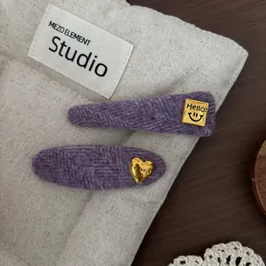 Detailed macro view of purple wool hair clips with gold metal hello and heart charms