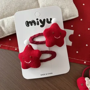 Détail de pinces à cheveux étoiles rouges tricotées avec broderie et pompons blancs