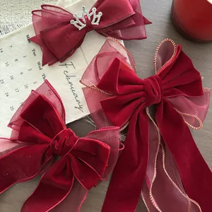 Dettaglio di fiocchi in velluto bordeaux con rete dai bordi dorati e corona di strass