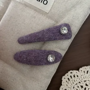Detailed macro view of purple herringbone tweed hair clips with large square rhinestones