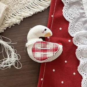 Detailopname van handgemaakte katoenen vogel haarclip met rood geruite vleugels