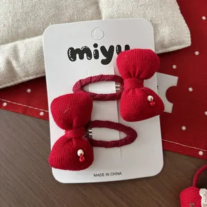Détails de deux barrettes nœuds en tricot rouge avec perles sur carte de présentation