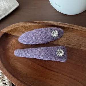 Close-up of purple plush hair clips with sparkling rhinestones on a wooden tray