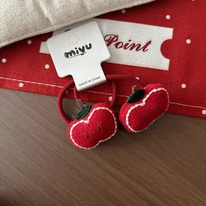 Détail de deux élastiques à cheveux pomme rouge tricotés main avec feuilles vertes