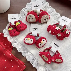 Close-up of red knitted children hair ties with cute cartoon bear and strawberry details
