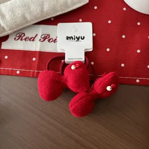 Gros plan sur élastiques à cheveux nœuds tricotés rouges avec perles sur fond à pois