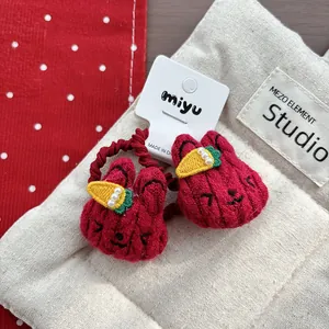 Detail of red knit rabbit hair ties with carrot decor and pearls for kids