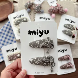 Detail of floral fabric hair clips with 3D bow on a miyu branded display card
