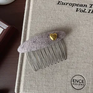Détail d'un peigne à cheveux en laine à fleurs avec cœur doré et dents en métal
