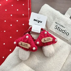 Detailed view of hand-knitted mushroom hair ties with white beads and red yarn texture
