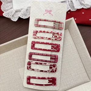 Détail de six barrettes rouges aux motifs léopard et carreaux sur une carte décorative