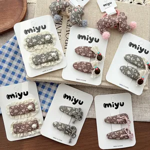 Detail of floral fabric hair clips with lace trim and plush bunny accessory on card