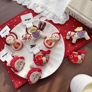 Detail of plush New Year hair ties with traditional embroidery on white card packaging