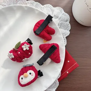 Detail of handmade red knitted hair clips featuring mushrooms and flowers on white ceramic plate