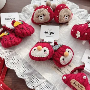 Close-up of handmade red knit hair accessories with cartoon bear and strawberry details