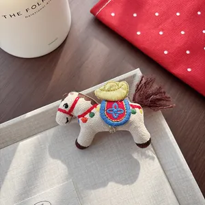 Detailed embroidery on a plush beige horse charm featuring a colorful folk style saddle