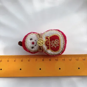 Detail shot of a festive red fabric hair clip with gold Fu character embroidery and ruler