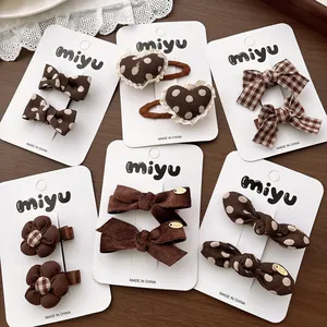 Lot de barrettes en tissu marron avec pois, dentelle et nœuds sur une carte de présentation