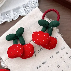 Dettaglio degli accessori per capelli a ciliegia in peluche rosso con pois su lino