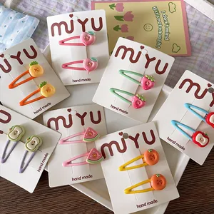 Detail of colorful fruit-themed hair clips set including peach and strawberry designs