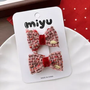 Close-up of pink and orange tweed bow hair clips with handmade gold metal tag detail
