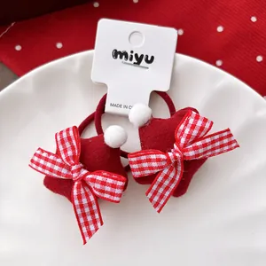 Macro view of plush red star hair ties with festive plaid bows and white pompoms