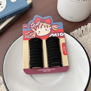 Close-up of 20 black seamless elastic hair ties on a cute cartoon girl packaging card
