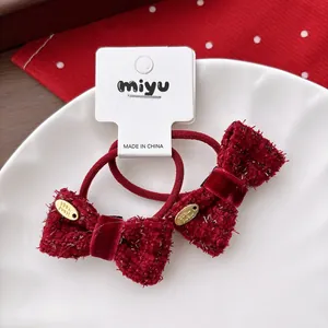Detailed close-up of dark red tweed bow hair ties with handmade metal charms