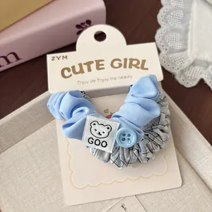 Dettaglio di scrunchies in tessuto a quadretti blu con patch a forma di orsetto