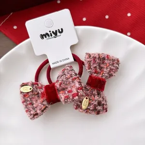 Detail of tweed bow hair ties with velvet accents and handmade gold charms in a dish