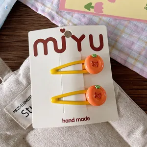 Detail of cute orange resin hair clips on handmade white display card for little girls