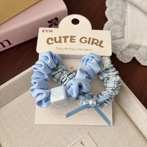 Dettaglio di elastici per capelli a scacchi blu chiaro con fiocco e perla su scheda