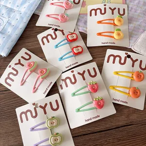 Close-up of colorful fruit hair clips with strawberry and apple resin details on cards
