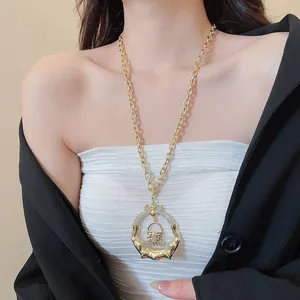 Detail of a chunky gold necklace with a crystal-embellished lip and lock pendant.