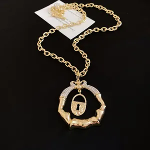 Detailed view of a gold chunky necklace with lock and crystal-studded ring pendant.