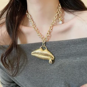 Statement chunky gold chain necklace with textured lip pendant on model