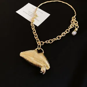 Macro view of textured gold 3D lip pendant on a chunky chain necklace detail