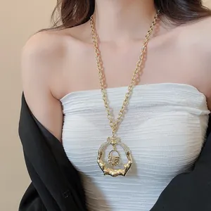 Detailed view of a chunky gold necklace with unique bamboo-ring and lock pendant.