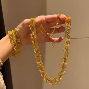 Macro view of the intricate gold pleated texture on this necklace and bracelet set.