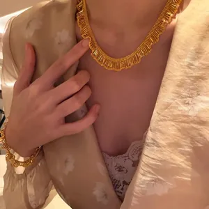 Detailed view of elegant vintage gold pleated fringe necklace and bracelet on model