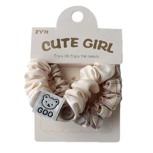 Set di due elastici per capelli a scacchi e satin con etichetta orsetto su carta