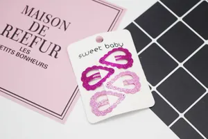 Lot de quatre barrettes à paillettes en forme de cœur rose et magenta sur carte